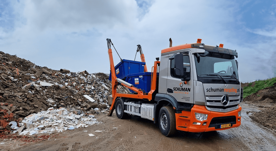 Wagen van Schuman Recycling plaatst een container op locatie bij een bedrijf
